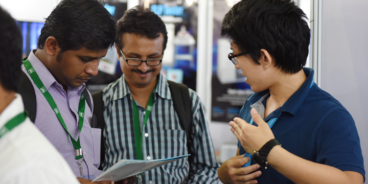 CeBIT India 2015の会場にて２人の男性客にINTERNET ACADEMYの説明を行うインターンシップ中の荒木大輝さん